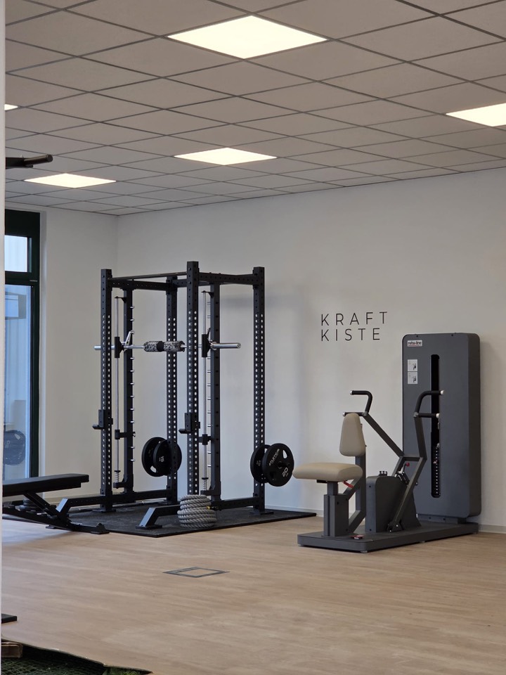 Trainingsbereich „Kraftkiste" bei AG Therapie mit Kraftstation, Hantelscheiben und Trainingsgerät